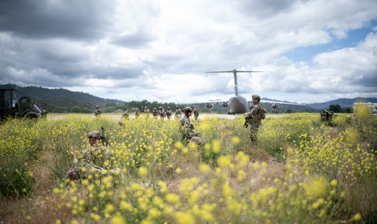 U.S. Marines assigned to 2nd battalion, 7th Marines, 1st Marine division, gather in a field after offloading from a C-17 Globemaster III aircraft assigned to Travis Air Force Base, California, at Schoonover Air Field at U.S. Army Fort Hunter-Liggett, California, May 5, 2023. Exercise Storm Crow is a readiness exercise apart of a larger scale exercise, Golden Phoenix, hosted by Travis Air Force Base with full spectrum support from partner units to include the 621st Contingency Response Wing, Joint Base McGuire Dix Lakehurst, New Jersey, the 349th Air Mobility Reserve Wing Travis AFB, California and the First Marine Expeditionary Force, Camp Pendleton, California. The purpose of the exercise is to demonstrate the combined ability to rapidly generate and project air power leveraging mobility platforms such as the C-5 Galaxy, C-17 Globemaster III and KC-10 Extender. (U.S. Air Force photo by Tech. Sgt. Dennis Hoffman)