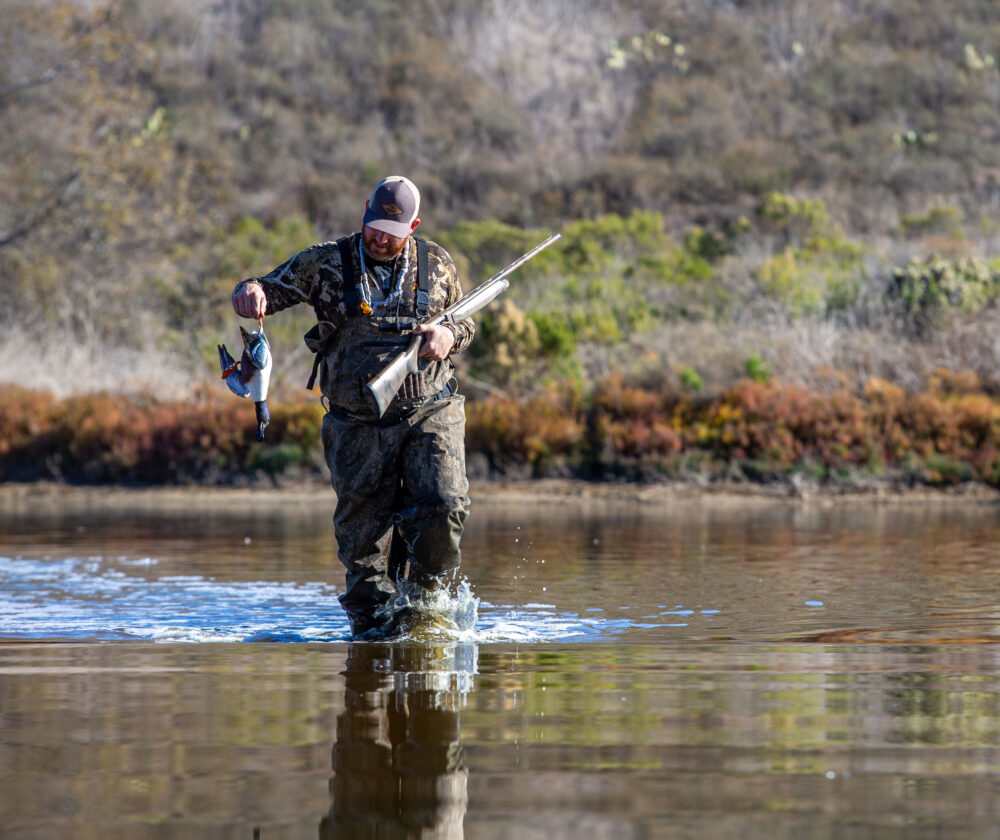 Eric Strand, a hunter with Born and Raised Outdoors, walks through Stuart Mesa Pond with a duck he shot during a waterfowl hunt on Marine Corps Base Camp Pendleton, California, Jan. 16, 2021. Pendleton Marines teamed up with Born and Raised Outdoors to enjoy the sport of hunting and help bring awareness to to the installation's wildlife conservation efforts. Pendleton’s game wardens allow hunting on base to aid in managing wildlife population levels. (U.S. Marine Corps photo by Lance Cpl. Andrew Cortez)