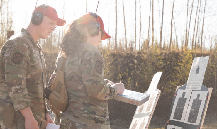 U.S. Air Force Staff Sgt. Brett Miner, left, 354th Security Forces Squadron combat arms training and maintenance trainer, and Senior Airman Megan Sheely Alvarado, 354th SFS CATM instructor, scores a participant's accuracy after an excellence in shooting competition at Eielson Air Force Base, Alaska, May 15, 2025. The competition was held during Police Week to honor law enforcement officers and security forces Airmen for what they contribute to their communities. (U.S. Air Force photo by Airman 1st Class Spencer Hanson)